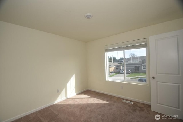 carpeted empty room featuring baseboards and visible vents