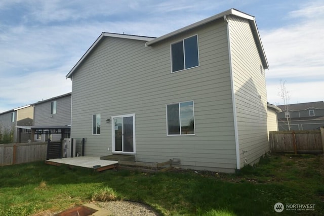 rear view of house featuring a lawn, a fenced backyard, and a deck