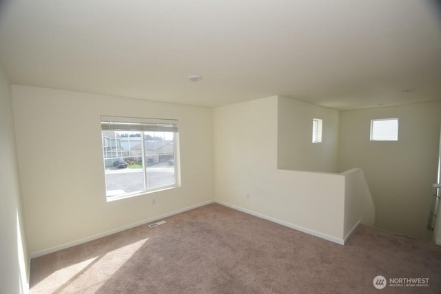 carpeted empty room featuring baseboards and visible vents