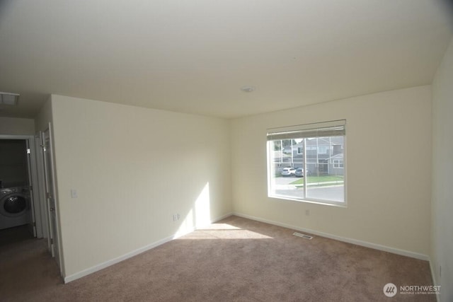 carpeted spare room with baseboards, washer / clothes dryer, and visible vents