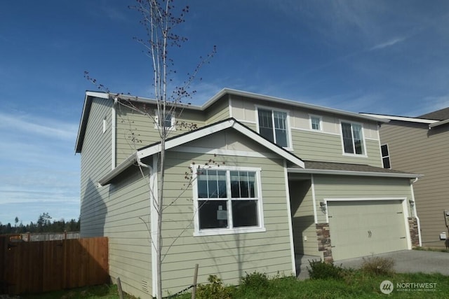 traditional home featuring concrete driveway, an attached garage, and fence