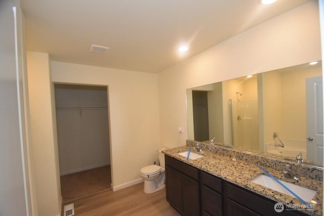 full bath with a sink, a garden tub, wood finished floors, and a spacious closet