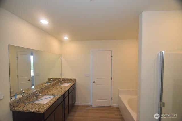 full bath with baseboards, a bath, a sink, and wood finished floors