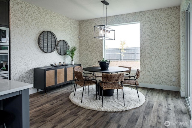9319 129th Street Ct NW, Gig Harbor, WA 98329 - dining space with dark wood finished floors, wallpapered walls, an inviting chandelier, and baseboards