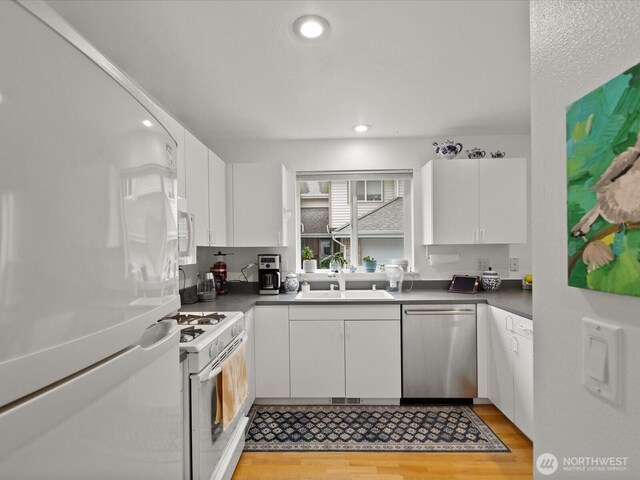 kitchen with a sink, white cabinets, light wood-type flooring, and white appliances