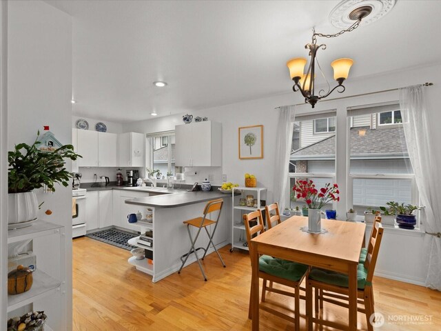 kitchen featuring open shelves, dark countertops, light wood-type flooring, white cabinetry, and a notable chandelier