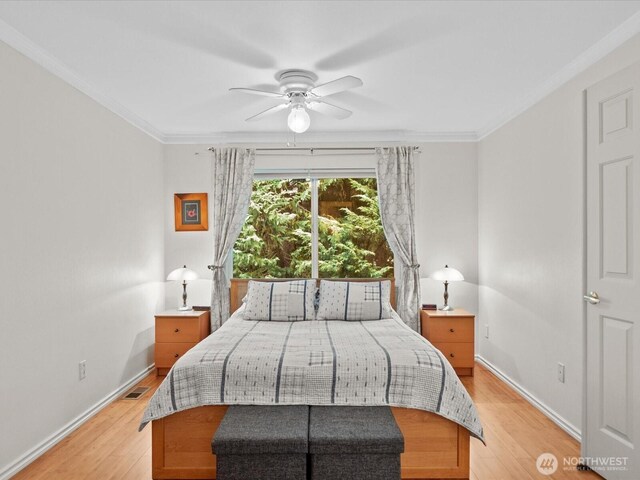 bedroom with light wood-type flooring, ornamental molding, baseboards, and visible vents