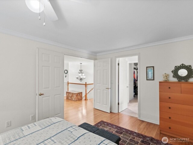 bedroom featuring crown molding, baseboards, an inviting chandelier, and light wood finished floors