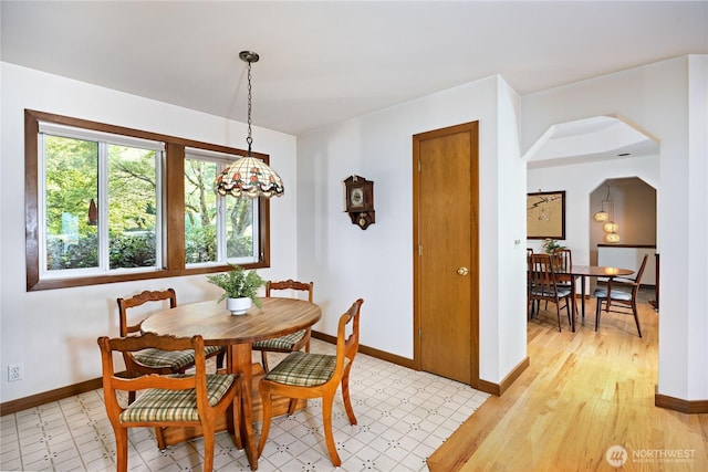 dining space with baseboards and arched walkways