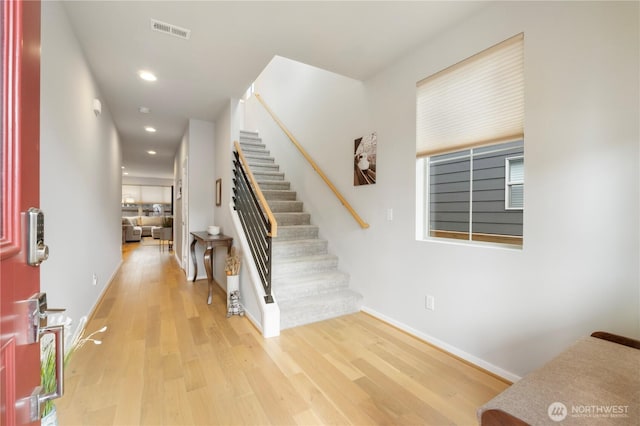 entrance foyer featuring baseboards, visible vents, light wood-style flooring, and stairway