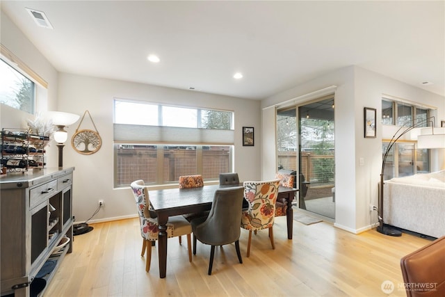 dining room with light wood-style floors, baseboards, a wealth of natural light, and visible vents