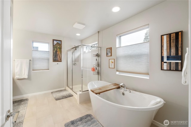 full bath with baseboards, a shower stall, and a soaking tub