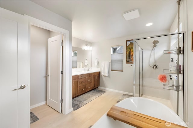 full bathroom featuring vanity, baseboards, a shower stall, and recessed lighting