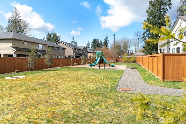 view of yard featuring a fenced backyard, a playground, and a residential view