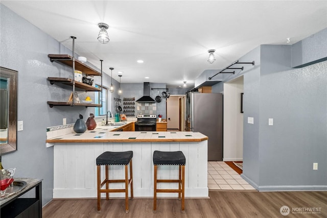 4715 NE Thunder Ln, Poulsbo, WA 98370 - kitchen with appliances with stainless steel finishes, a sink, wall chimney exhaust hood, a peninsula, and wood finished floors