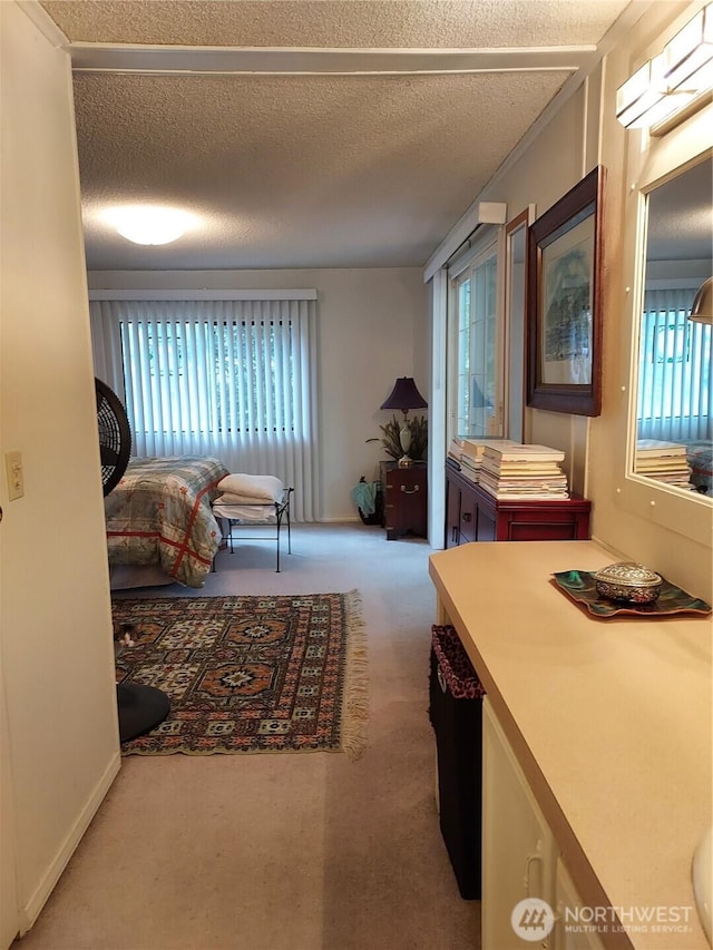 carpeted bedroom with multiple windows, a wall mounted air conditioner, and a textured ceiling