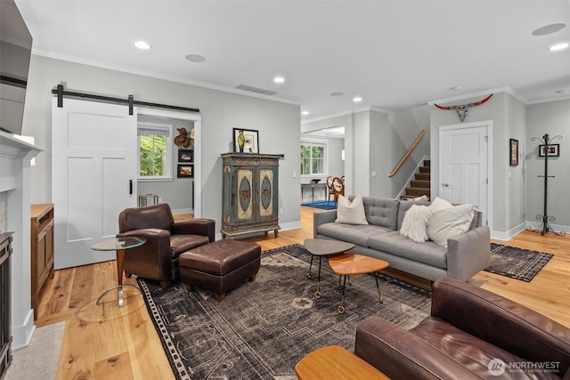 living area featuring a barn door, stairs, and light wood-style flooring