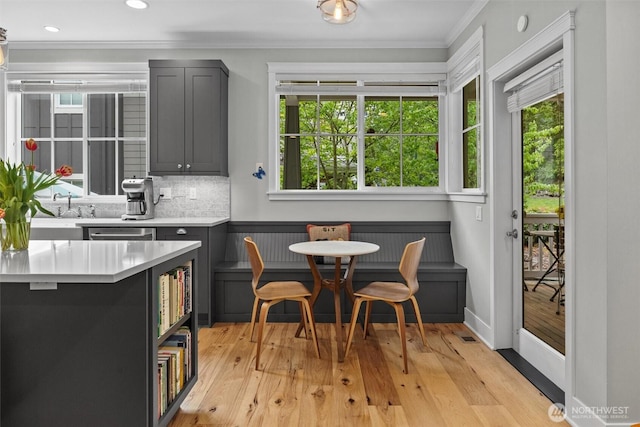 kitchen with ornamental molding, light countertops, tasteful backsplash, light wood-style flooring, and gray cabinetry