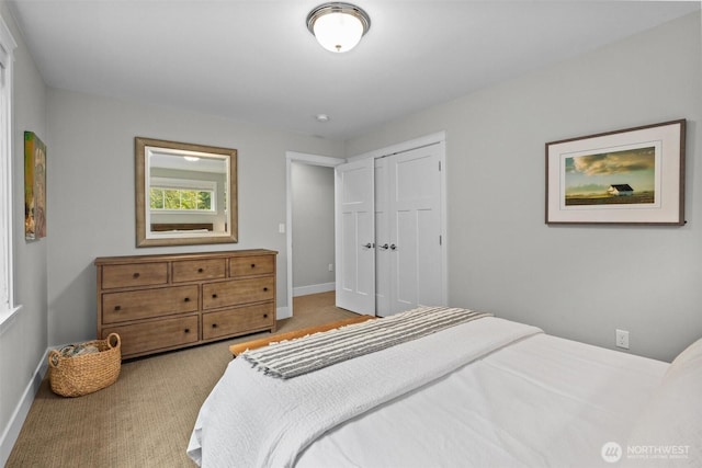 carpeted bedroom featuring baseboards and a closet