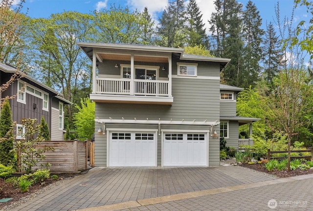 view of front of home with fence, an attached garage, driveway, and a balcony