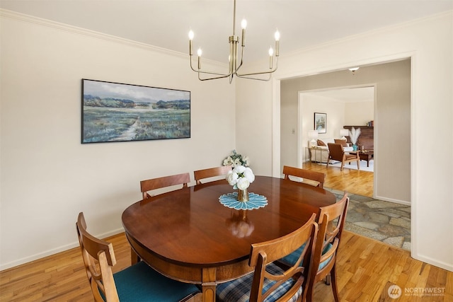 dining room featuring crown molding, light wood finished floors, baseboards, and a chandelier