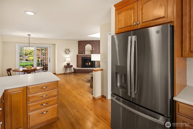 kitchen featuring stainless steel fridge, light countertops, brown cabinets, and light wood-type flooring