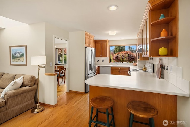 kitchen featuring plenty of natural light, white electric stove, a peninsula, open floor plan, and stainless steel fridge