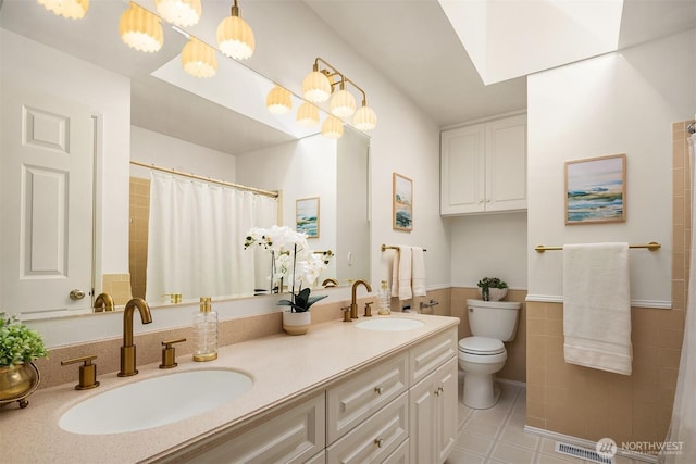 full bathroom featuring toilet, tile walls, a sink, and tile patterned flooring