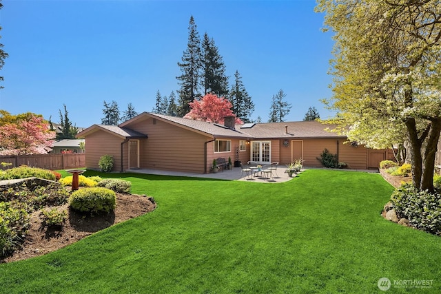 rear view of house featuring fence, a patio, a chimney, and a lawn