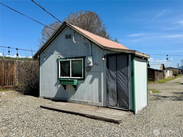 view of outdoor structure featuring fence and an outbuilding