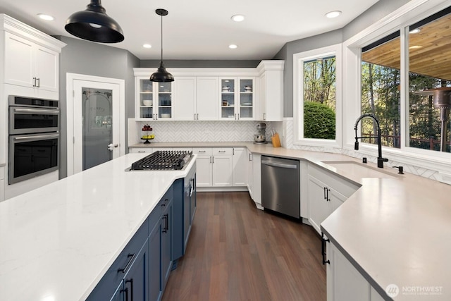 kitchen featuring white cabinets, stainless steel appliances, a sink, and blue cabinets