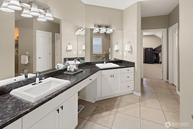 full bathroom with double vanity, tile patterned floors, a sink, and a walk in closet