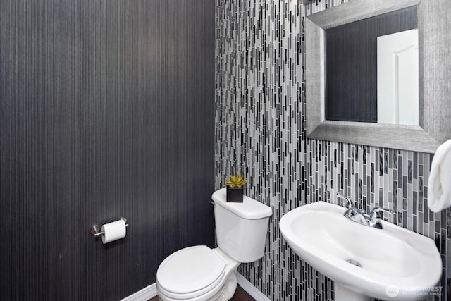 bathroom with toilet, a sink, and tasteful backsplash
