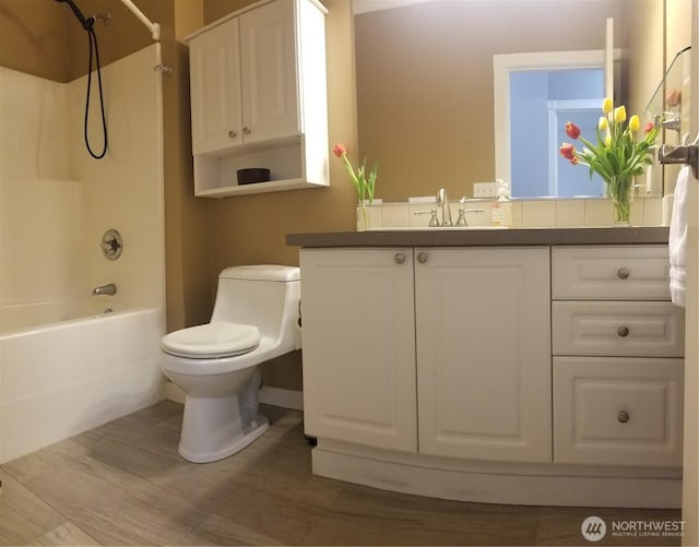bathroom with toilet, vanity, wood finished floors, and tub / shower combination
