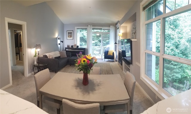 carpeted dining space featuring vaulted ceiling and baseboards