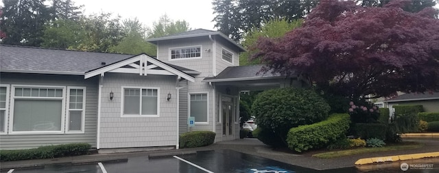 view of front of home with uncovered parking and a shingled roof