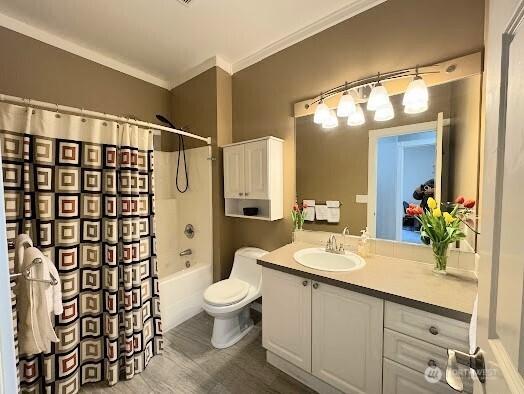 full bath with vanity, toilet, ornamental molding, shower / bath combo, and wood finished floors