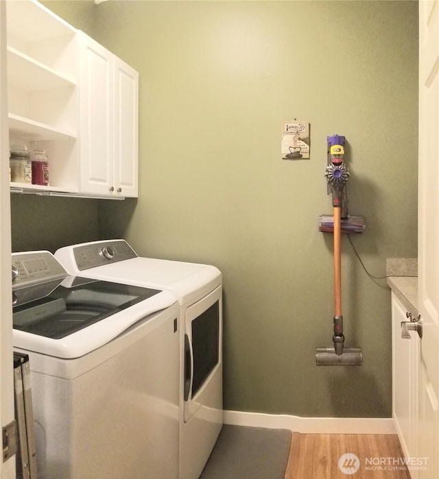 laundry area with cabinet space, washing machine and clothes dryer, baseboards, and light wood-style floors
