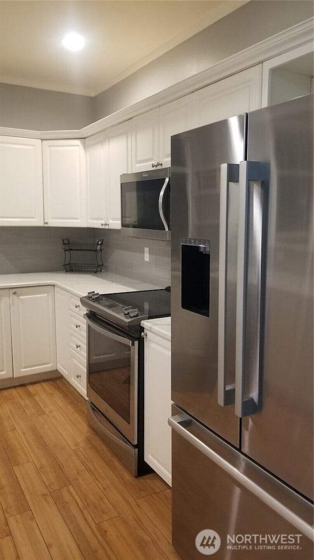 kitchen featuring appliances with stainless steel finishes, white cabinets, and light wood-type flooring
