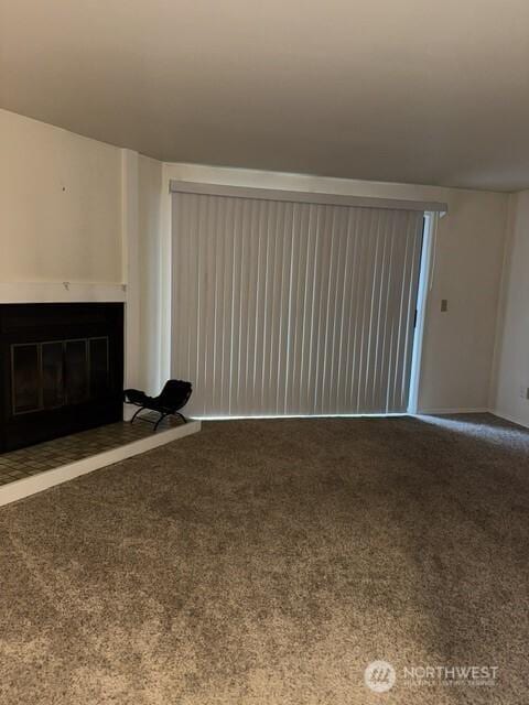 unfurnished living room featuring carpet floors, baseboards, and a glass covered fireplace