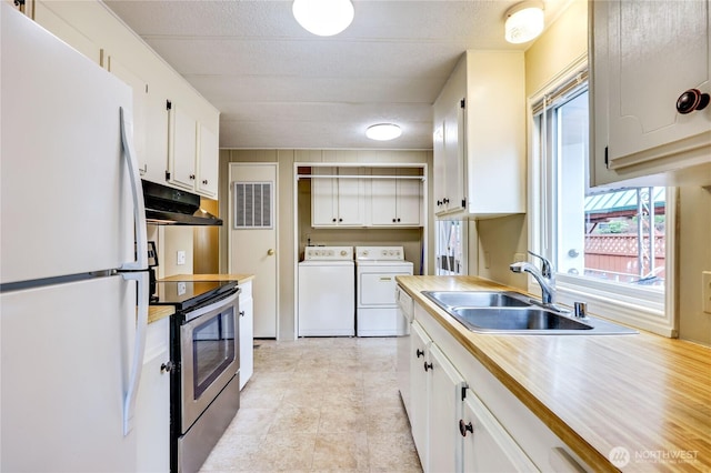 kitchen with washing machine and clothes dryer, stainless steel range with electric cooktop, a sink, freestanding refrigerator, and under cabinet range hood