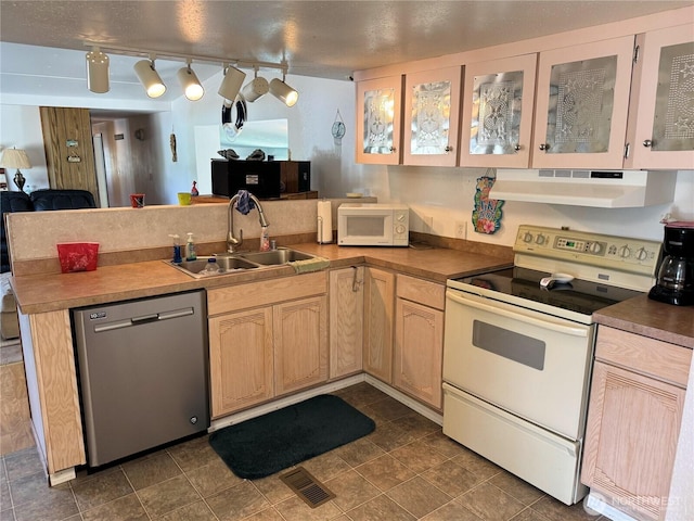 kitchen featuring a sink, visible vents, under cabinet range hood, white appliances, and a peninsula