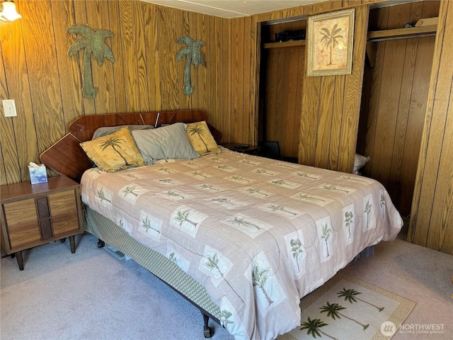 bedroom with wooden walls, a closet, and carpet flooring