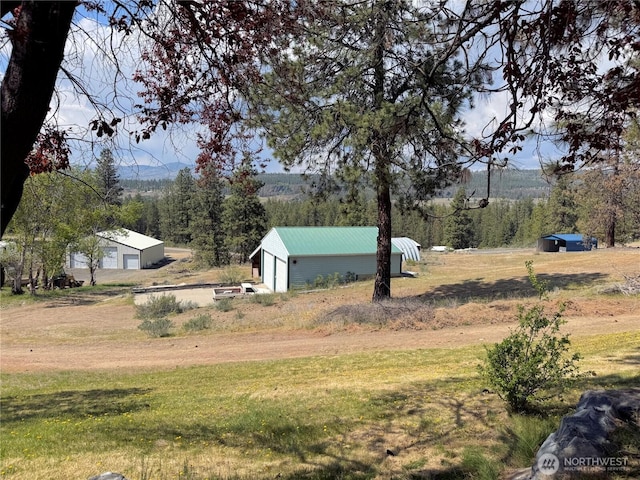 view of yard with an outbuilding, a detached garage, and a rural view