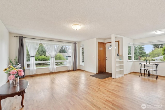 living room with a healthy amount of sunlight, a textured ceiling, and light wood-style flooring