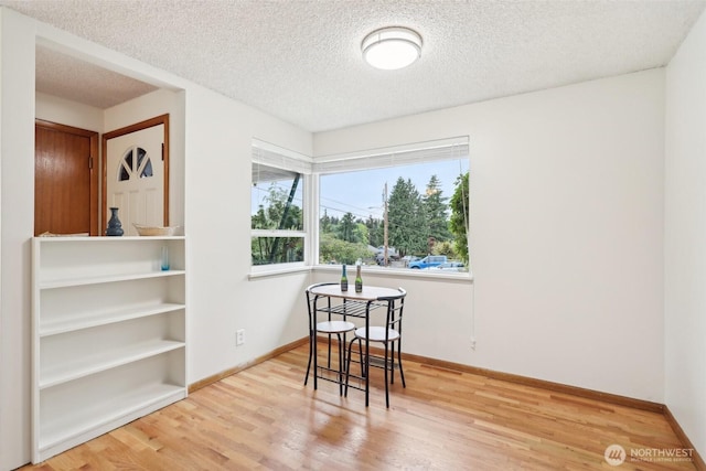 dining room with a textured ceiling, baseboards, and wood finished floors
