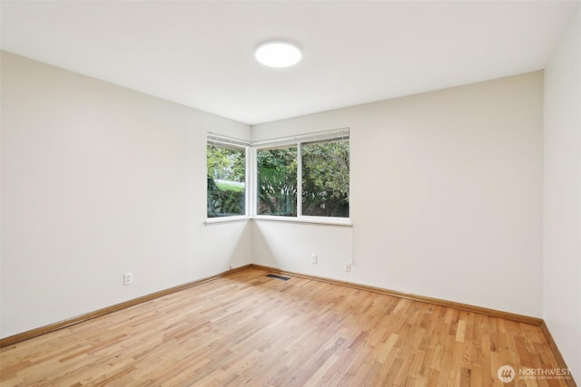 spare room with baseboards, light wood finished floors, and visible vents