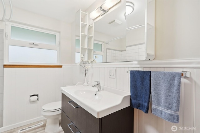 bathroom with vanity, wainscoting, visible vents, and toilet