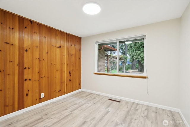 empty room with baseboards, wood finished floors, and visible vents