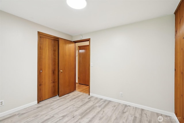 unfurnished bedroom with a closet, baseboards, and light wood-type flooring
